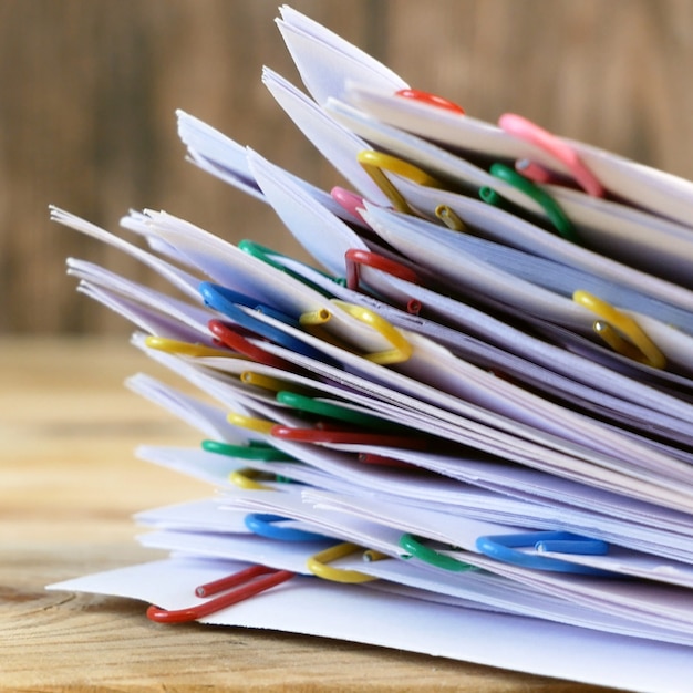 Hand takes stack of documents with binder clips wooden table, closeup