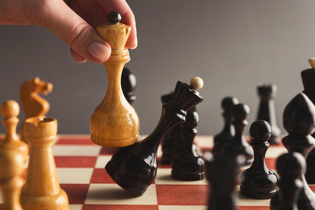 Hand taking checkmate on chessboard during chess game. Successful strategy, victory, business, win, intelligence and education.