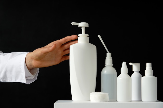 Hand taking hand sanitizer and liquid soap on black background