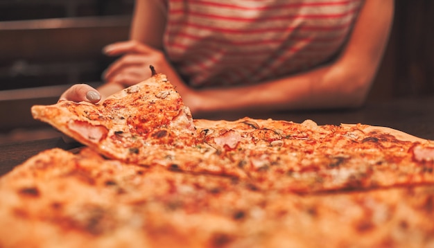 Hand taking a piece of pizza, close-up