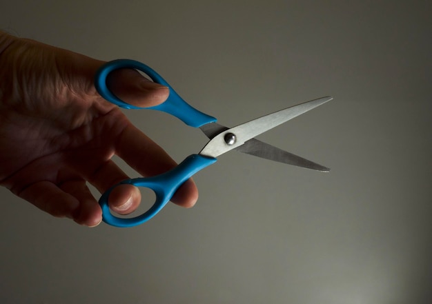 Фото Рука берет ножницы, чтобы подстричь голубые ножницы