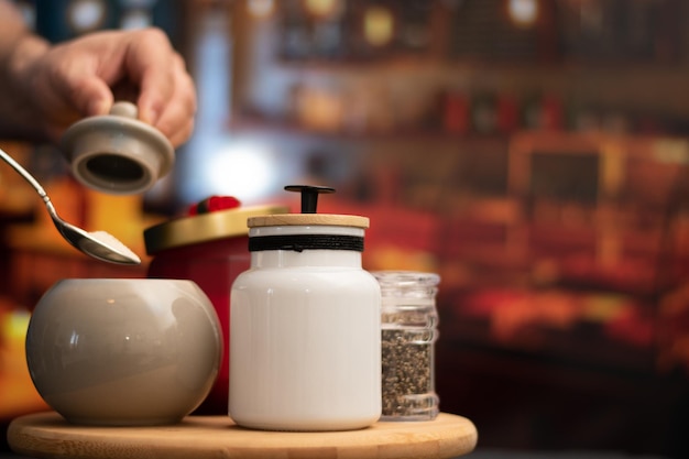 Hand taking sugar from mugs of sugar and containers over a table