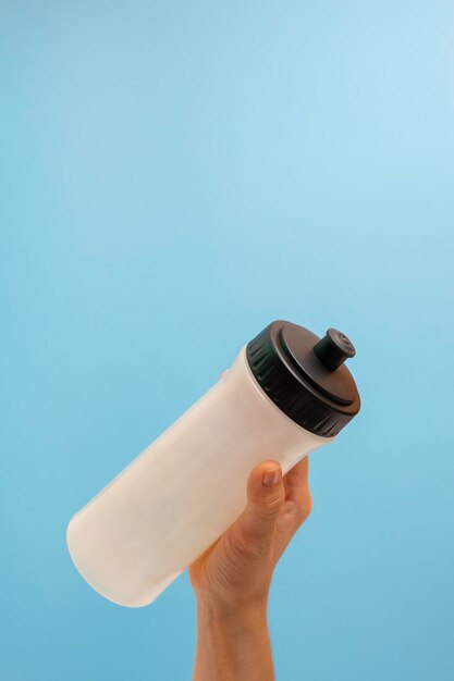 Photo hand taking a white and black canteen on a blue background copy space