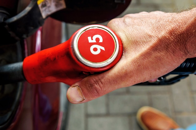 Hand, tanken van een personenauto. Brandstofpomp met het nummer 95. Bovenaanzicht.