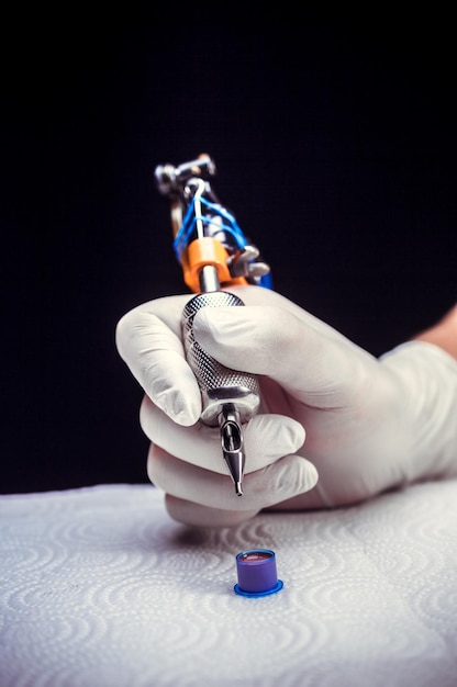 Hand of a tattoo artist with a tattoo machine.