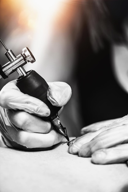 Hand of Tattooist in Rubber Gloves Drawing a Tattoo with Electric Tattoo Gun Closeup