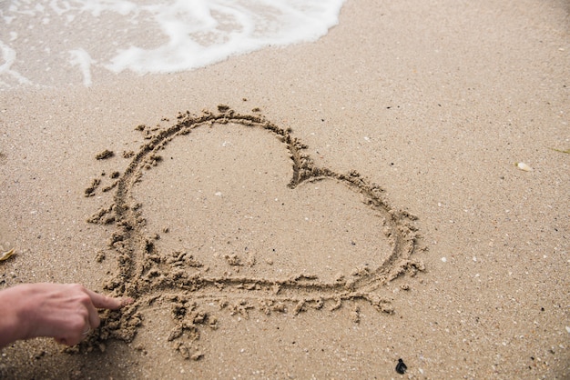 Hand tekenen hart vorm op zand