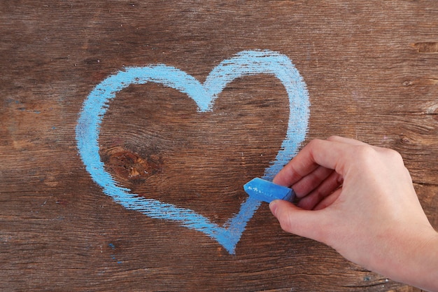 Hand tekent hart van krijt op houten bord