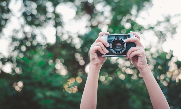 The hand that is holding up holds the old camera to take a picture.