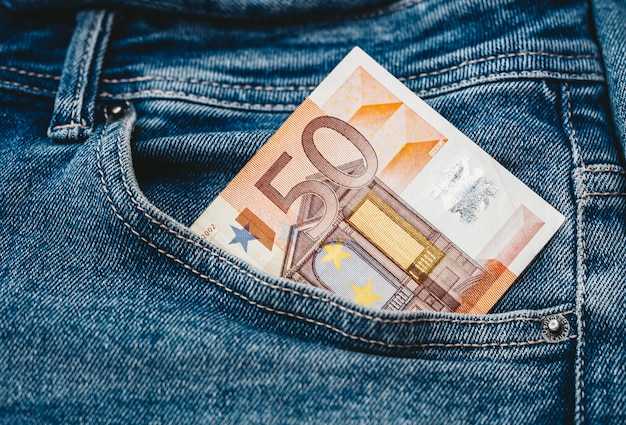 The hand that puts euro banknotes in a pocket of jeans