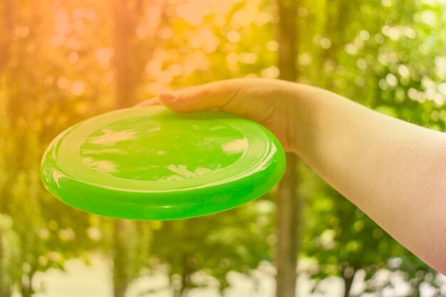 Hand throwing a frisbee disc in the park on a summer day