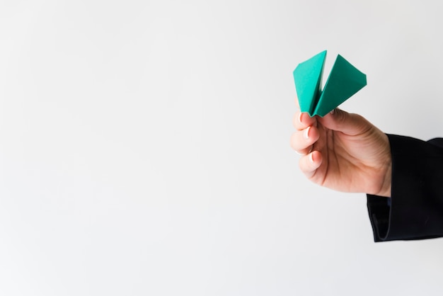 hand throwing green paper plane