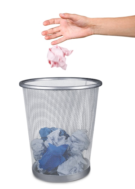 Hand throwing out paper into trash basket isolated on white