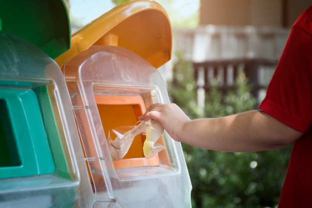 Hand throwing plastic bag into recycling bin, concept of environmental protection