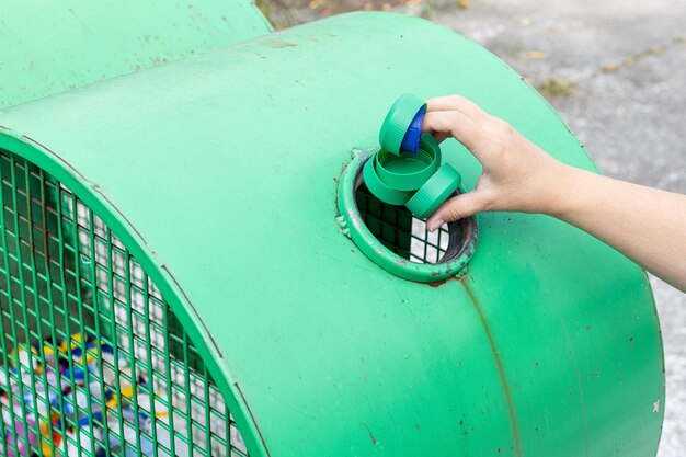 Hand throwing plastic caps into a urban recycling bin Environment and global friendly concept