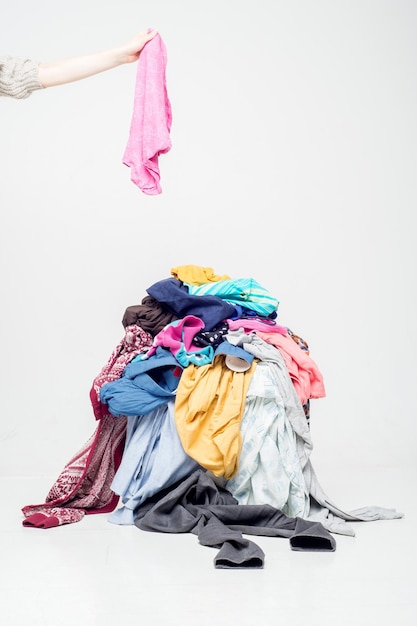 Photo hand throws clothes into a pile with used clothes pile of used clothes. second hand for recycling