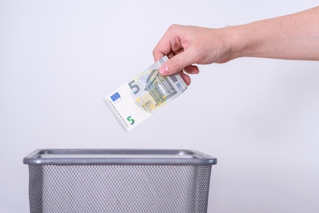 The hand throws five euros in the trash