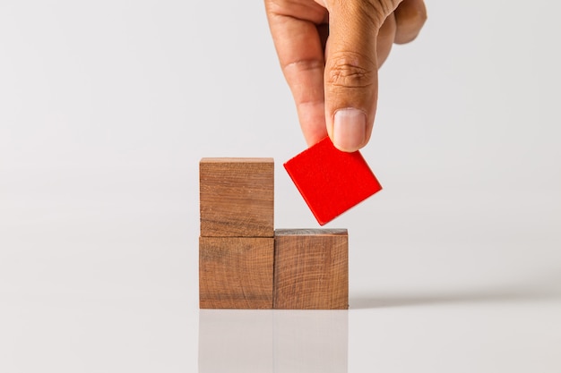 Hand toevoegen van het laatste ontbrekende houten blok op zijn plaats. Succes bedrijfsconcept.