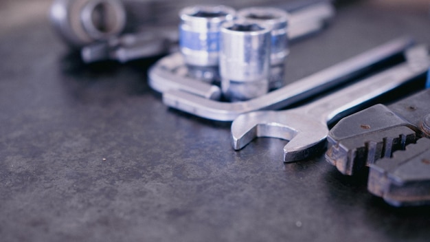 Hand tools consisting of wrenches pliers socket wrenches laid out on old steel plate background