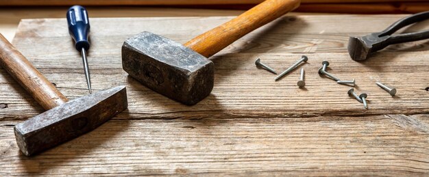 Hand tools old used hammer sledgehammer plincers and nail on
wood work bench table