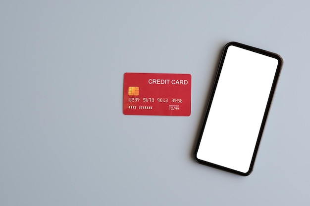 Hand touch leeg scherm mobiele telefoon en creditcard geïsoleerd op een grijze achtergrond