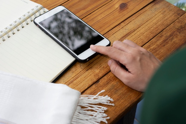 Tocco della mano sullo schermo smart phone mobile al tavolo di legno