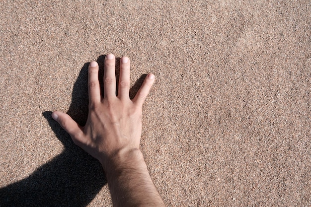 Hand touches quartz sand Point of view