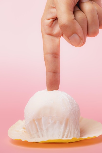 写真 食べ物やパン屋のコンセプトのピンクの背景においしいイチゴ大福日本のお餅に触れる手