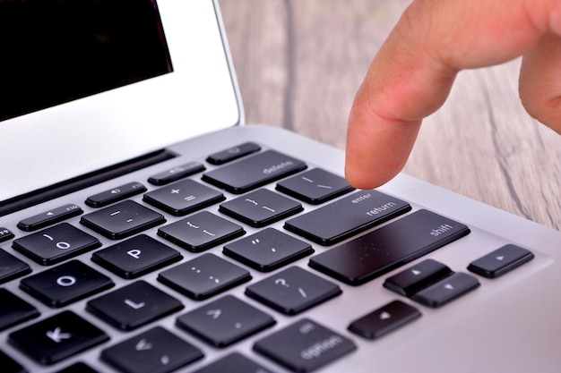 Photo hand touching laptop computer keyboard - focus on the keyboard