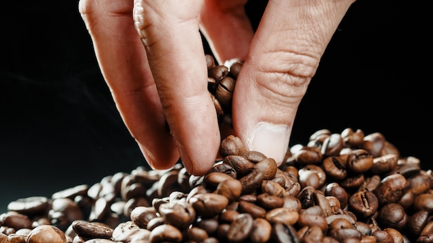 Foto mano che tocca i chicchi di caffè arrostiti