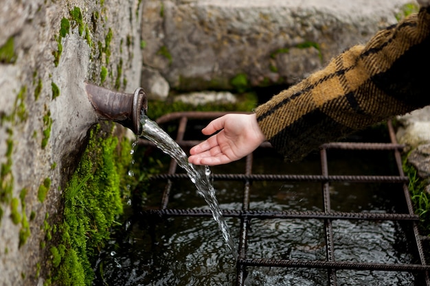 Hand touching water from a natural fountain