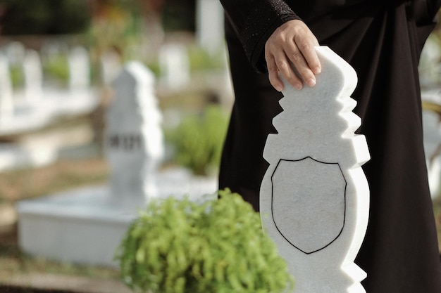 a hand touching the white marble tombstone at a muslim cemetary
