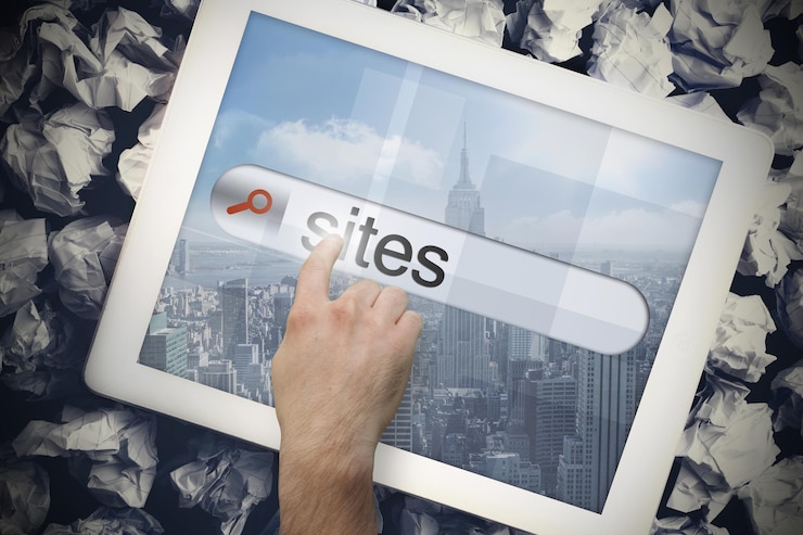 फोटो hand touching the word sites on search bar on tablet screen on crumpled papers