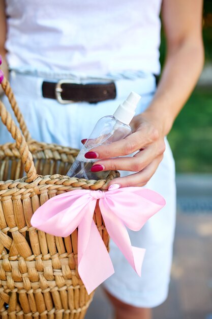 Hand of trendy woman in with straw bag with disinfecting hands gel in handbag