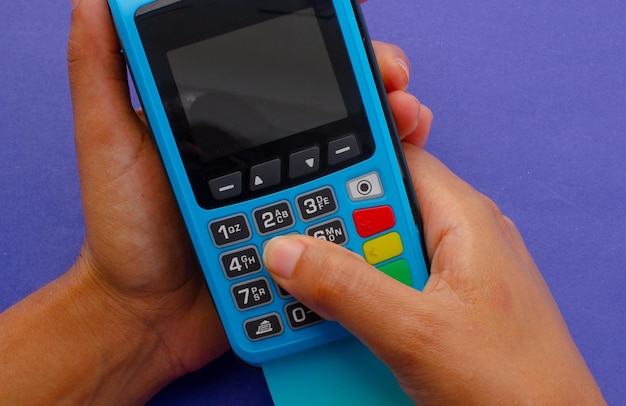 Hand typing credit password Credit card payment machine POS terminal and bank card Concept of payments cash credit card purchases Blue credit card machine with number keys and display screen