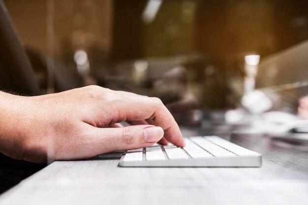 Hand typing on a wireless keyboard with acrylic plexiglass separator setting on the office desk