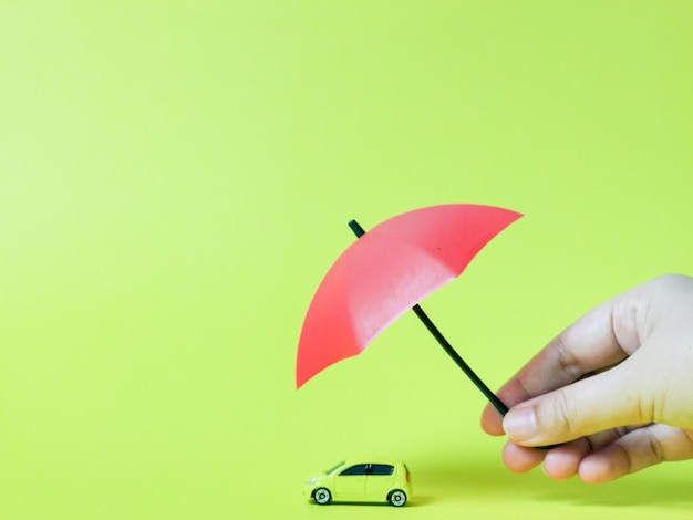 Photo hand and umbrella as protection of car insurance concept