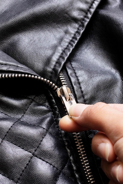 Photo hand unbuttones lock of black leather jacket