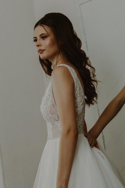 The hand of an unrecognizable bridesmaid straightens the dress of the bride looking in the mirror closeup side view