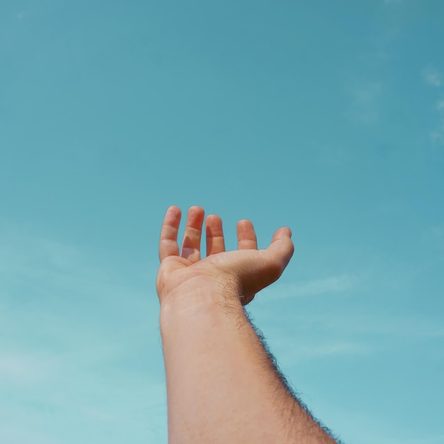 Alzare la mano gesticolando nel cielo blu, sentimenti ed emozioni