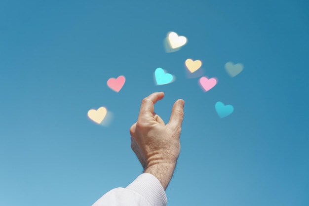 Alzare la mano nel cielo toccando una forma di cuore, amare le emozioni a san valentino