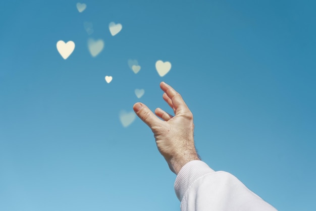 Alzare la mano nel cielo toccando una forma di cuore, amare le emozioni a san valentino