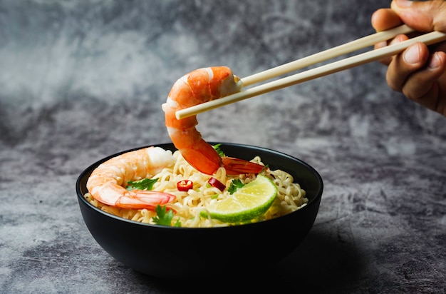 Photo hand using chopsticks pickup instant noodles on concrete background.