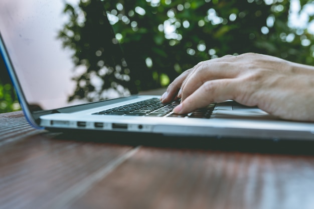 Hand using computer laptop PC in garden