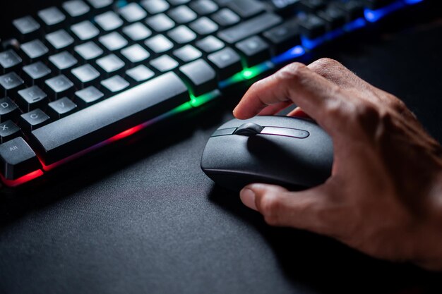 RGBキーボードの隣にコンピュータマウスを手で使用する