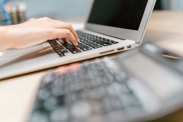 Hand using laptop on working table in office