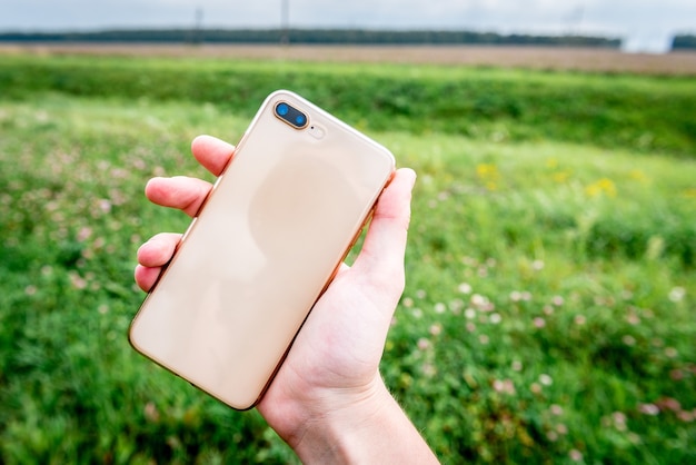 Hand using a phone on a grass