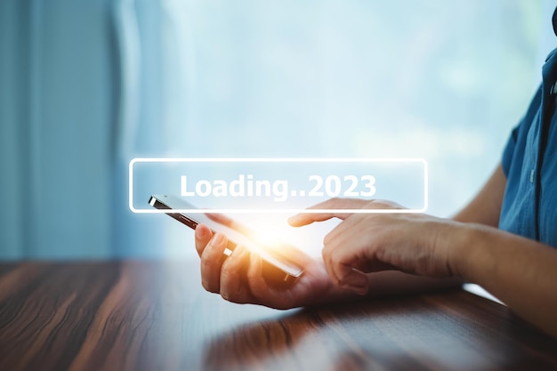 2023 로드를 위해 막대에서 스마트폰 검색을 사용하여 손으로 2023년 새해 개념 시작