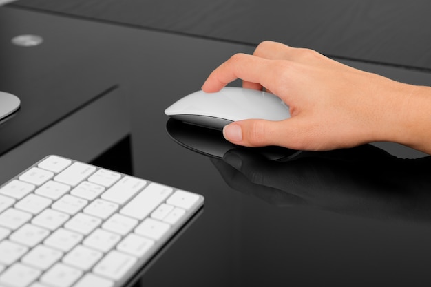 Hand using wireless mouse on black table