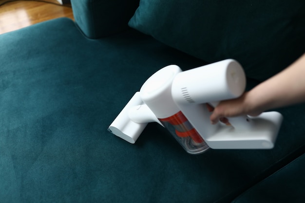 Hand vacuums upholstered furniture in apartment